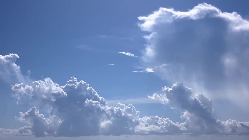 A time-lapse of majestic white cumulonimbus clouds building and evolving against a vibrant blue sky