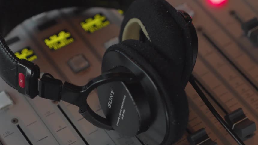 A close-up shot of a pair of headphones resting on a professional sound mixing board in a recording studio