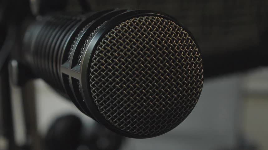 A close-up, static shot of a professional black broadcast microphone in a recording studio
