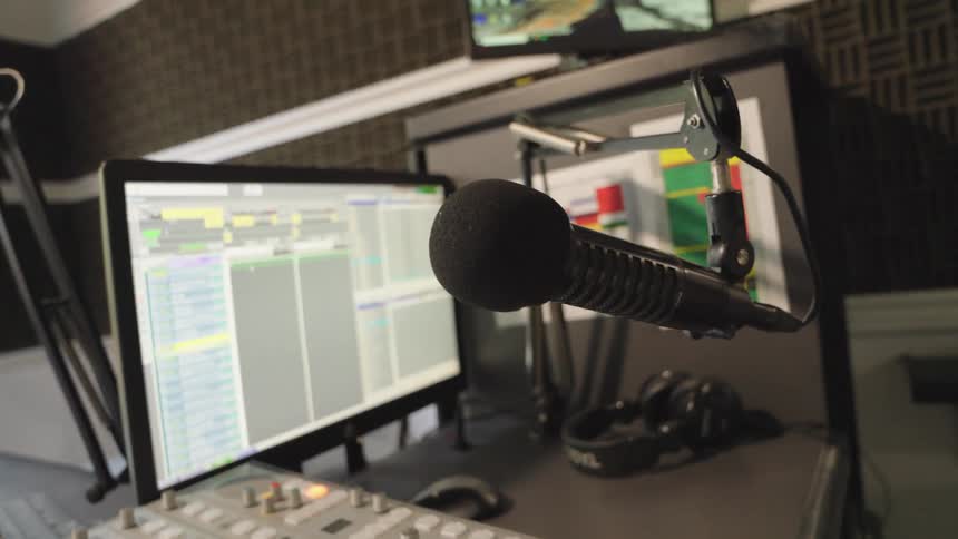 A slow push-in shot focuses on a microphone in an empty radio station broadcasting studio