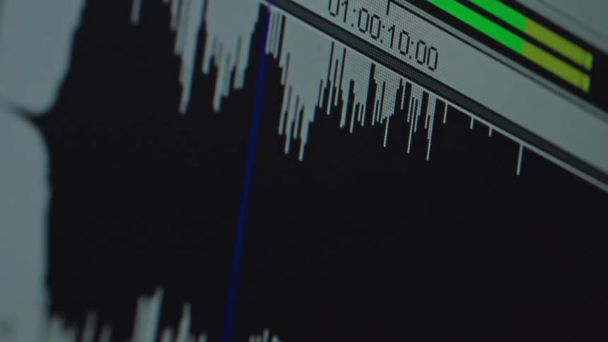 A close-up view of an audio waveform playing back on a digital editing software timeline