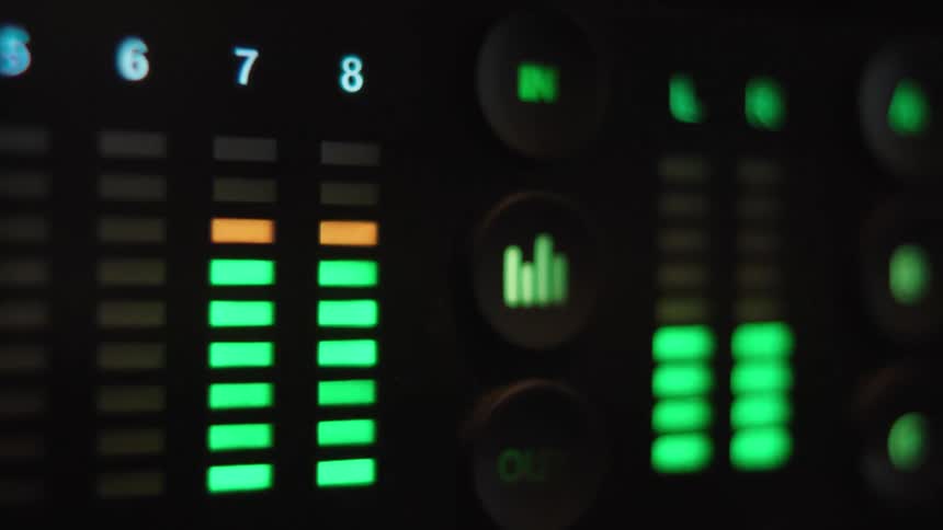Flashing green LED audio level meters on a digital sound mixer in a dark studio