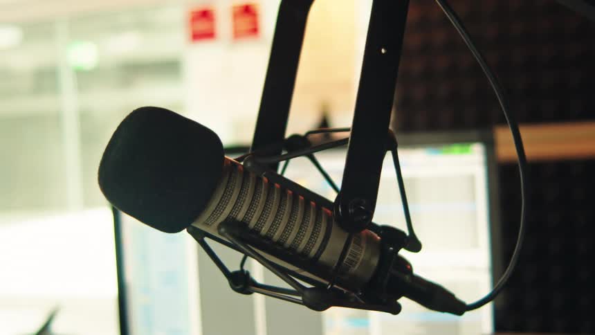 Close-up slow pan of a professional broadcast microphone hanging in a recording studio