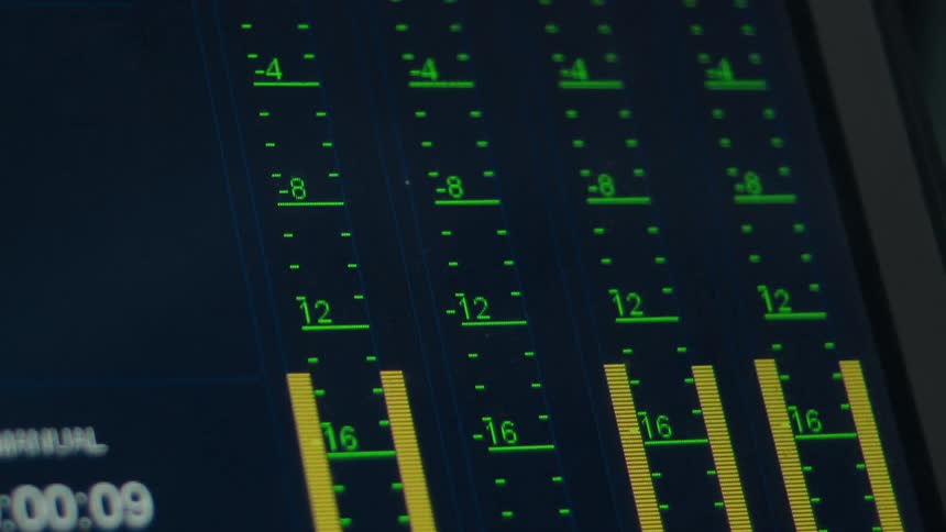 Close-up of a digital audio mixing console screen showing fluctuating sound levels on the VU meters