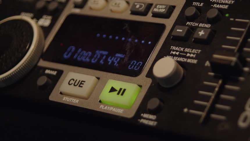 Close-up of a DJ's finger pressing the illuminated play button on a modern digital turntable, starting the track