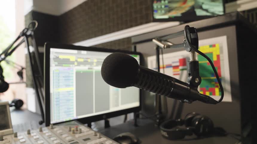 Dolly shot of a professional microphone and sound mixing console in an empty radio broadcast studio