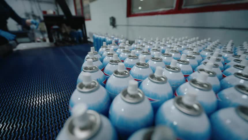A large batch of aerosol spray cans move along a factory production line