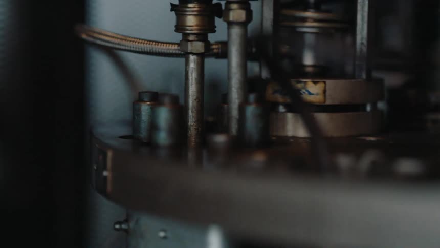 A detailed close-up shot shows the inner workings of an industrial machine in slow motion