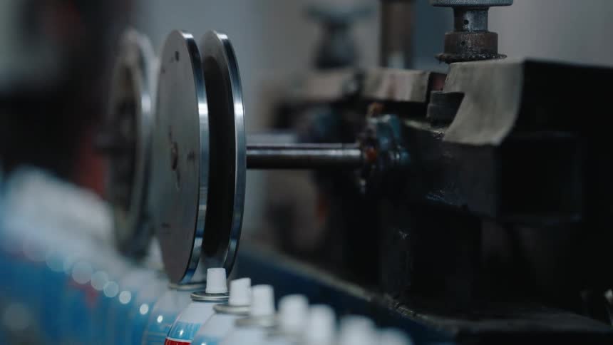 Close-up of aerosol spray cans moving along a factory conveyor belt during production