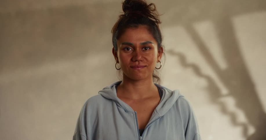 Cinematic portrait of a young woman in a hoodie looking directly at the camera with a calm expression