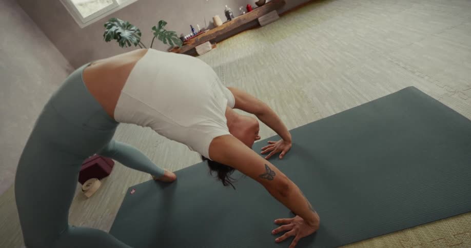 A flexible yogi gracefully performs a slow-motion deep backbend yoga transition in a peaceful, sunlit studio