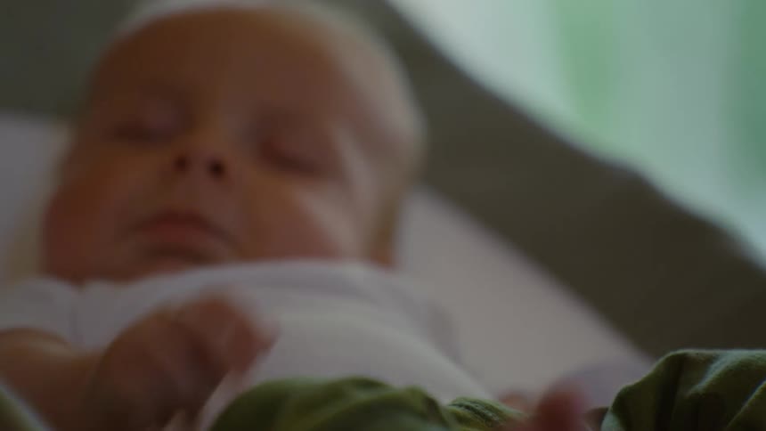 A serene close-up shot captures a newborn baby sleeping peacefully, starting with a focus on its tiny feet before revealing its tranquil face