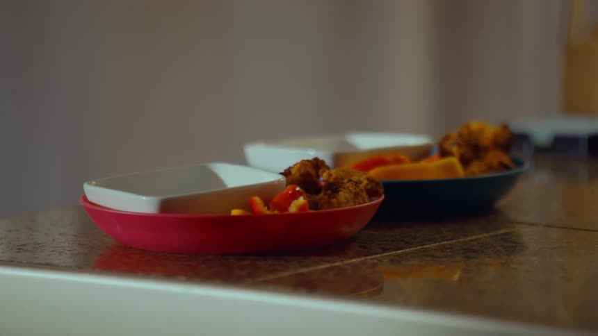 A static close-up shot of two colorful bowls filled with fried appetizers and vegetables ready to be served on a kitchen counter