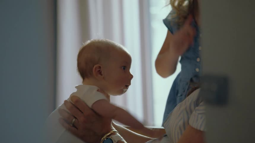 A big sister and mother affectionately kiss a new baby in a tender family moment at home
