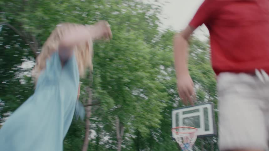 Energetic slow motion footage of a young boy and girl laughing and jumping on a trampoline in their backyard