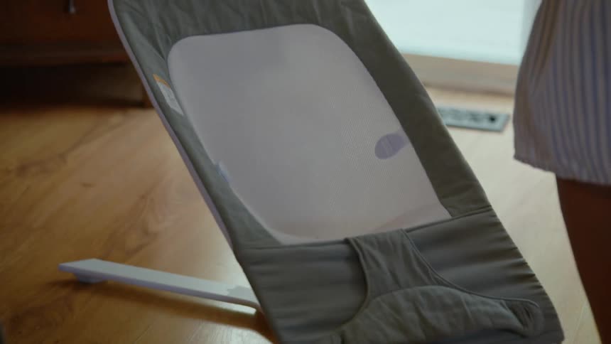 A loving mother takes her sleepy newborn from her husband and gently places the infant in a bouncer to rest