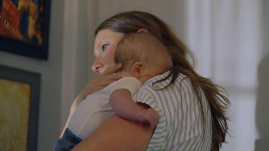 A tender and loving moment as a mother holds her newborn baby over her shoulder