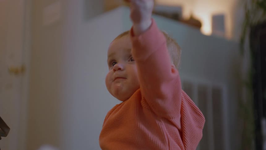 An adorable baby is given a cracker by their parent, curiously inspects it, and then joyfully shares a piece back