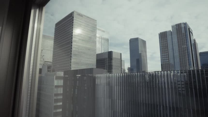 A view of modern glass skyscrapers in a bustling city from a high-rise window on a hazy day