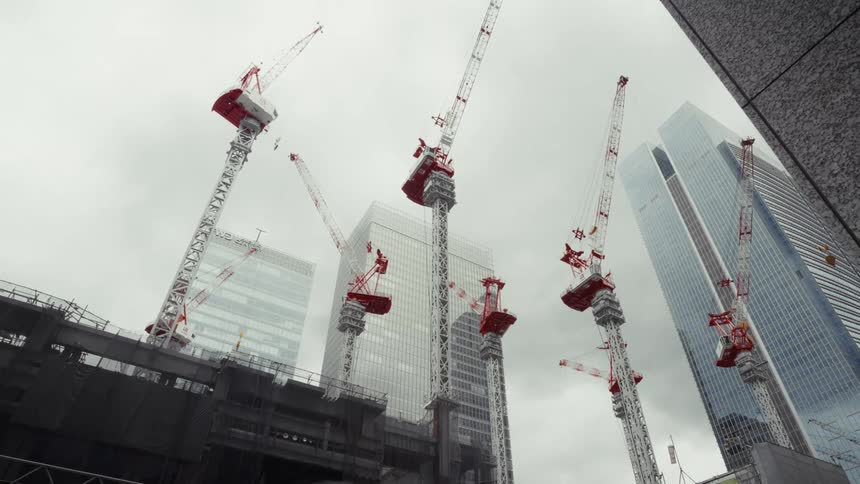 Time-lapse of multiple construction cranes at a skyscraper building site on an overcast day in a modern city