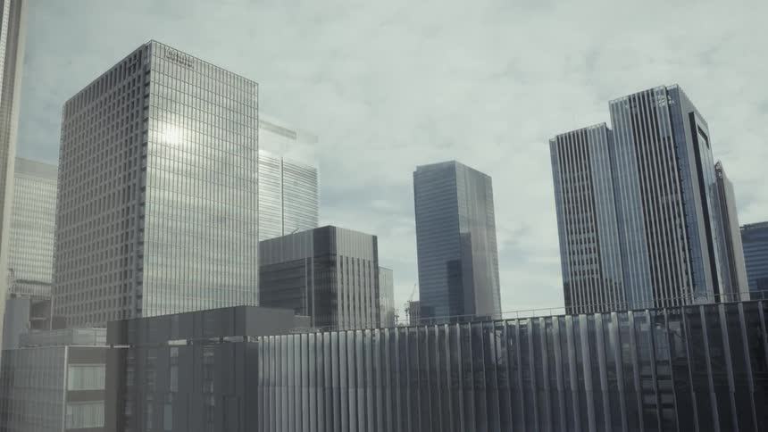 A static shot of a modern city's financial district under a gray, overcast sky