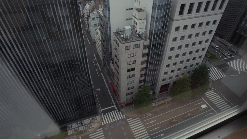 A high-angle time-lapse from a window captures cloud shadows moving across the quiet streets of a modern city