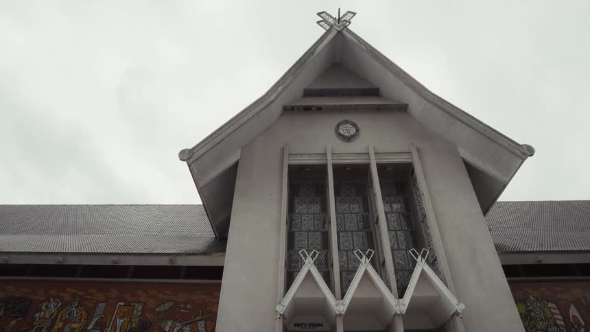 A low-angle shot of the unique architecture of a building's main entrance under an overcast sky