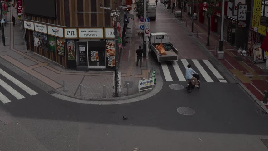 High angle view of pedestrians and a cyclist passing by a quiet street corner in a Japanese city