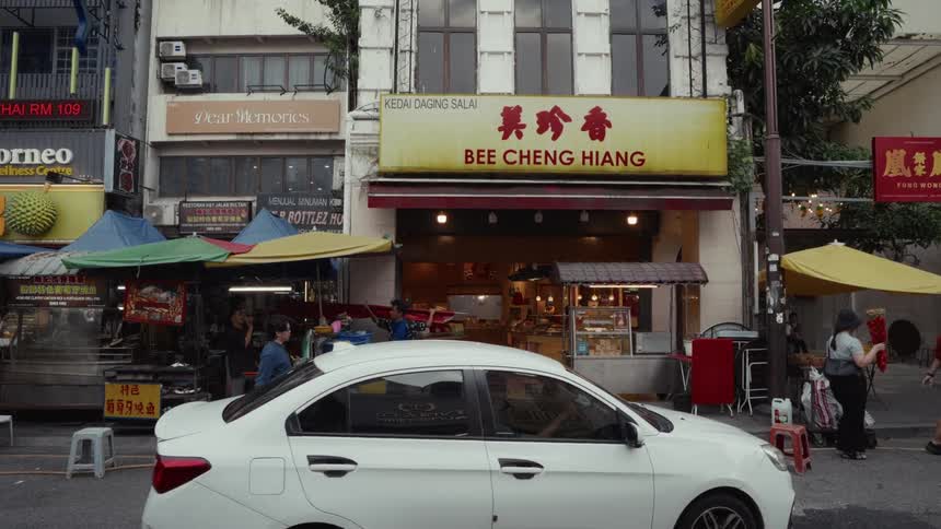 Pedestrians walk past the Bee Cheng Hiang storefront on a busy street in Kuala Lumpur, Malaysia