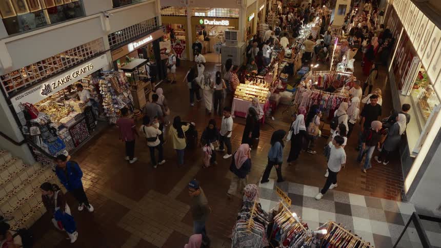 A high-angle view captures a bustling crowd of people shopping at a vibrant indoor market