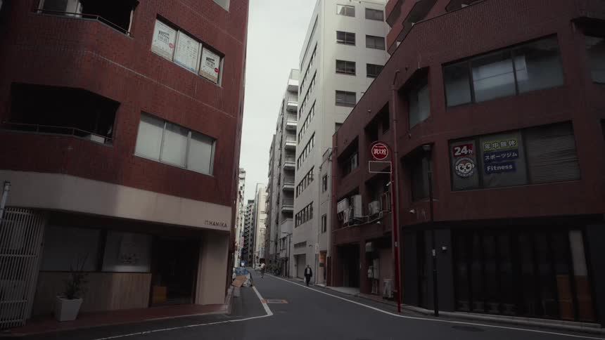 A static view down a quiet, narrow street flanked by modern apartment and office buildings in Tokyo, Japan