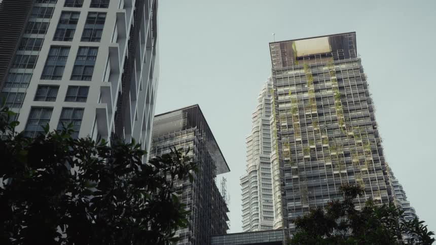 A low-angle view of modern futuristic skyscrapers with green vertical gardens towering over trees