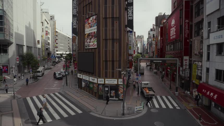 An elevated view of a relatively quiet street corner in Tokyo, Japan, as people cross the street on an overcast day