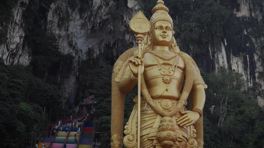 A static shot of the giant golden Lord Murugan statue guarding the entrance to the Batu Caves in Malaysia