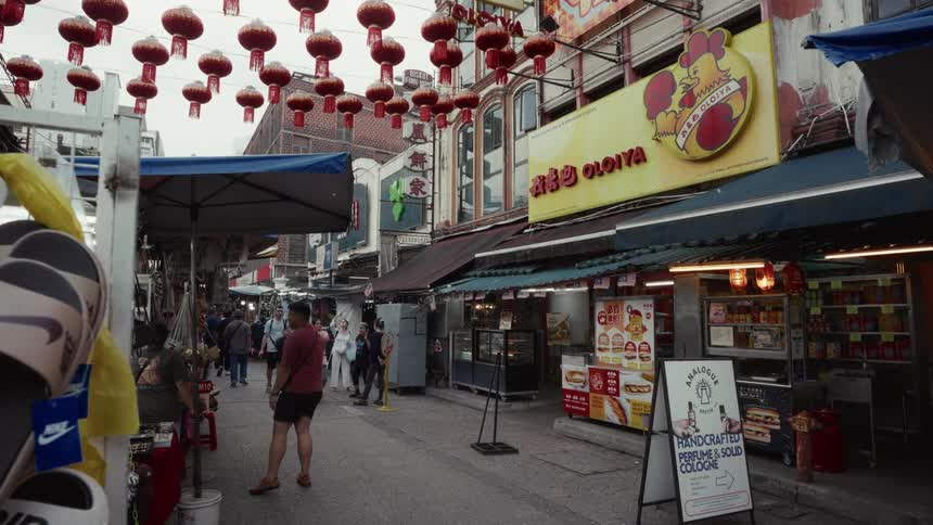 Shoppers browse through a vibrant Asian street market adorned with traditional red paper lanterns