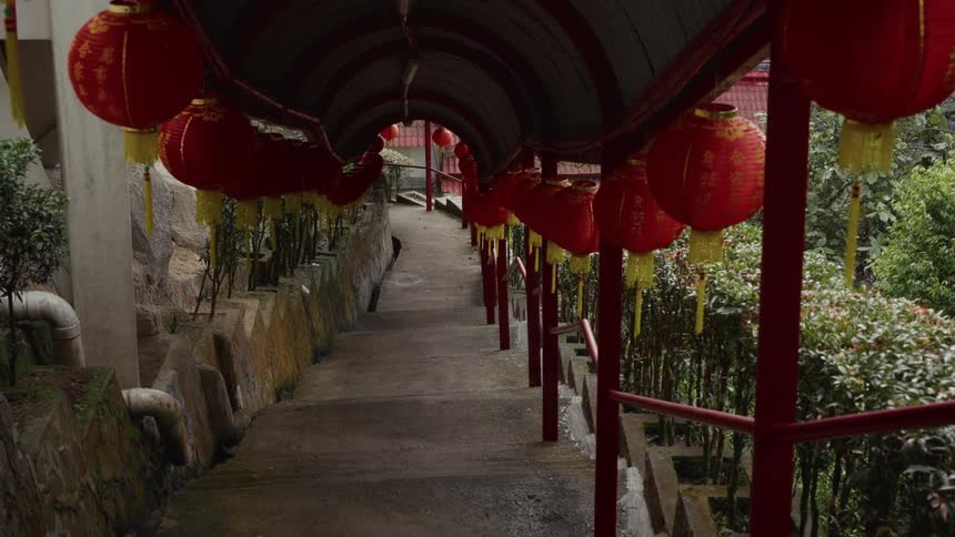 A slow zoom out reveals a covered walkway adorned with traditional red Chinese lanterns leading down a set of stairs