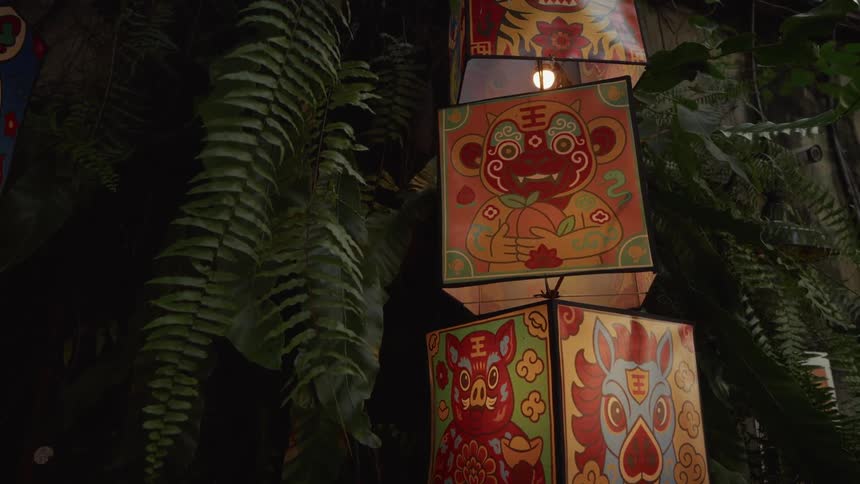 Festive Chinese zodiac lanterns featuring a monkey, pig, and horse hang amongst lush green ferns