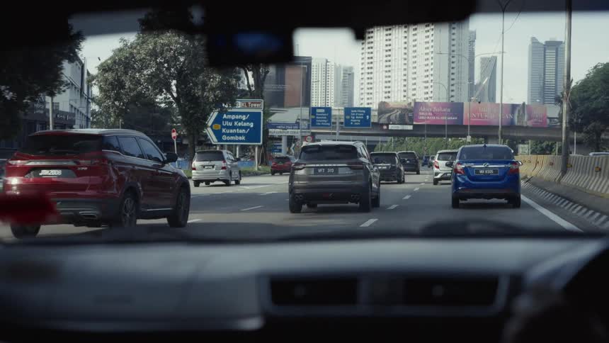 A point-of-view shot from a car moving slowly in traffic on a busy city highway during the daytime