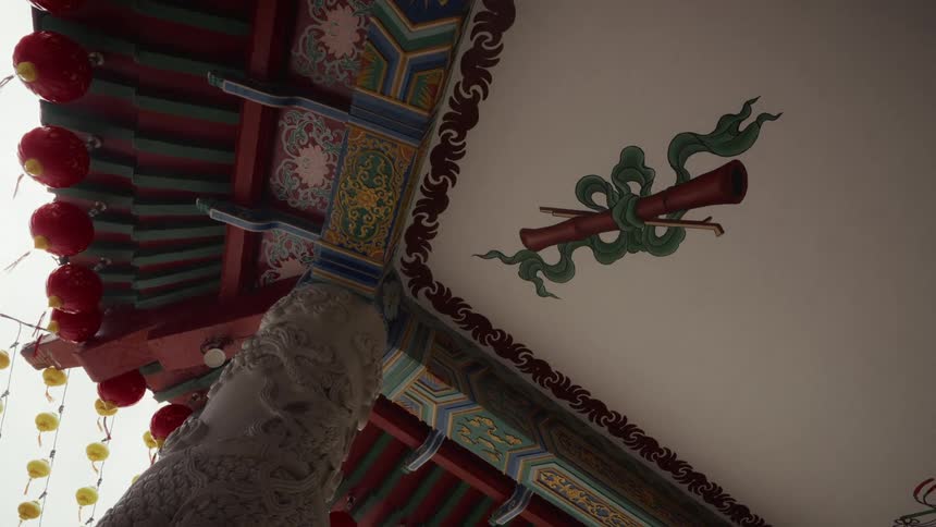 Intricate details of a traditional Chinese temple ceiling, showcasing a carved dragon pillar, colorful painted eaves, and hanging lanterns