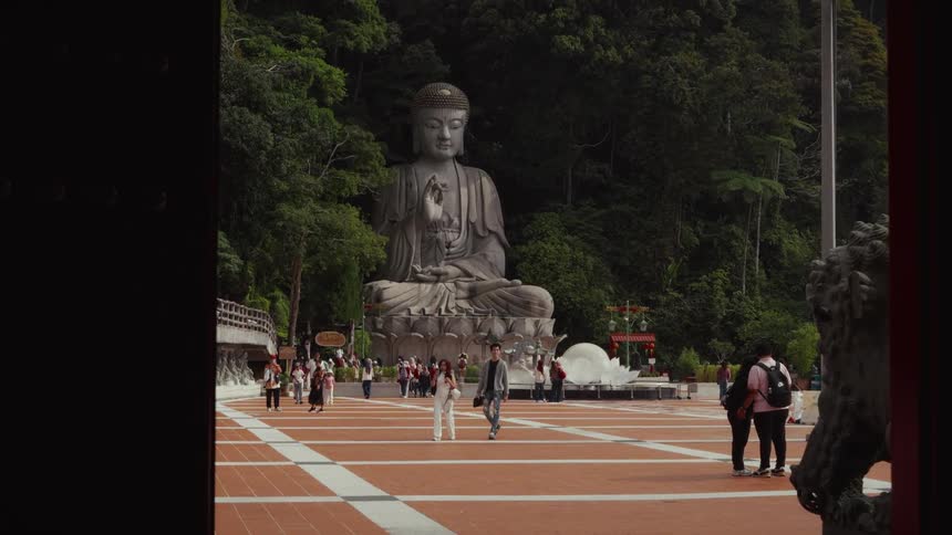 Tourists admire the giant seated Buddha statue at the Chin Swee Caves Temple, set against a lush jungle backdrop
