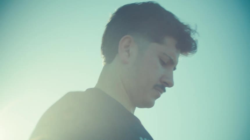 A determined young male soccer player in a USA jersey mentally prepares for a match in the bright sunlight, captured in slow motion