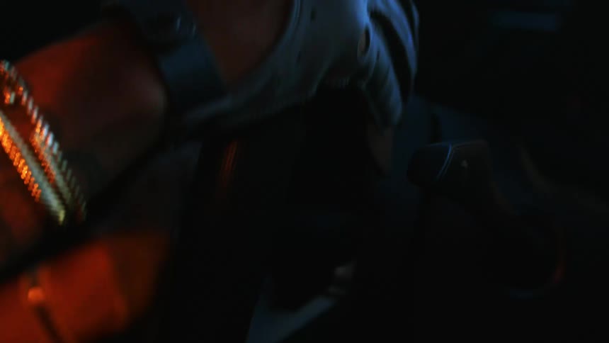 A person wearing stylish driving gloves and gold bracelets tightly grips the steering wheel during a tense night drive