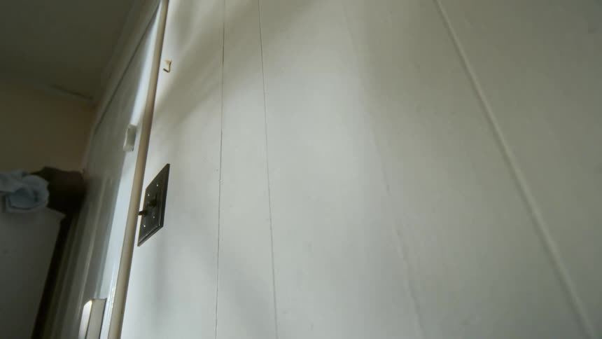 Close-up time-lapse of natural sunlight casting moving shadows across a plain interior wall