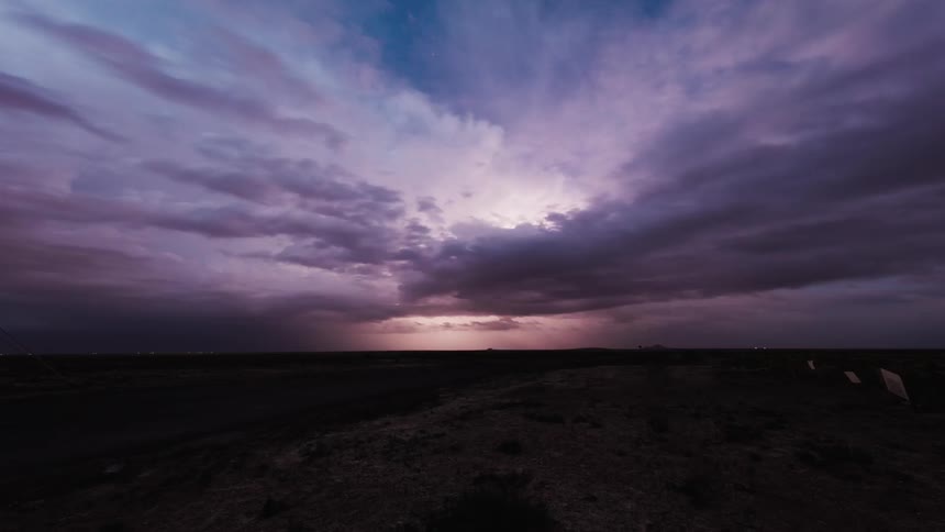 A storm passes by a long field at dawn