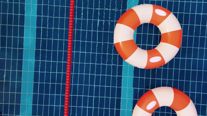 An overhead view of colorful inflatable rings and balls floating in a swimming pool
