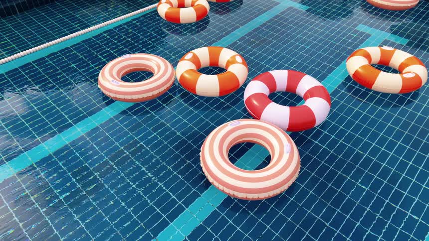 Colorful striped inflatable rings float gently on the shimmering water of a blue-tiled swimming pool