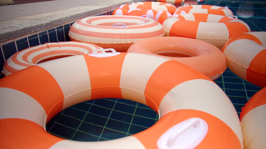 Orange and white striped inflatable rings float together in a tranquil, blue-tiled swimming pool
