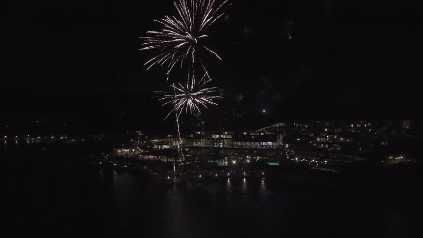 Spectacular aerial view of fireworks exploding in the night sky over a luxurious seaside resort