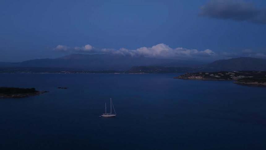 A tranquil aerial view reveals sailboats anchored in a peaceful bay during the serene blue hour after sunset