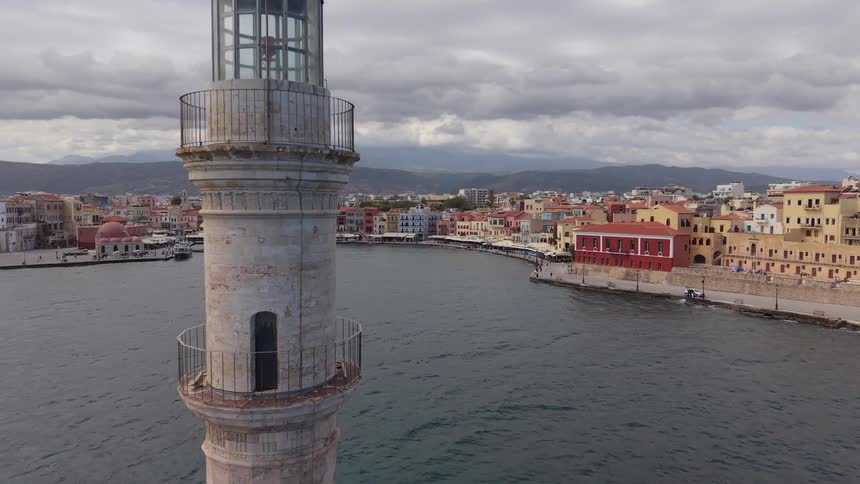 Aerial view flying past the old lighthouse into the Venetian harbor of Chania in Crete, Greece